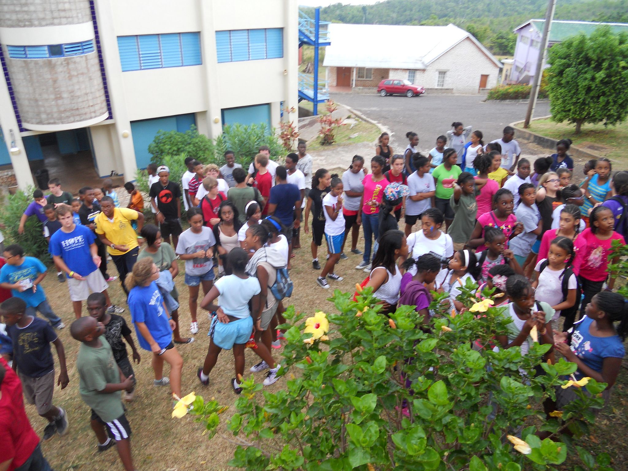 A whole camp gathered on a hillside lawn in Jamaica, waving up at the camera