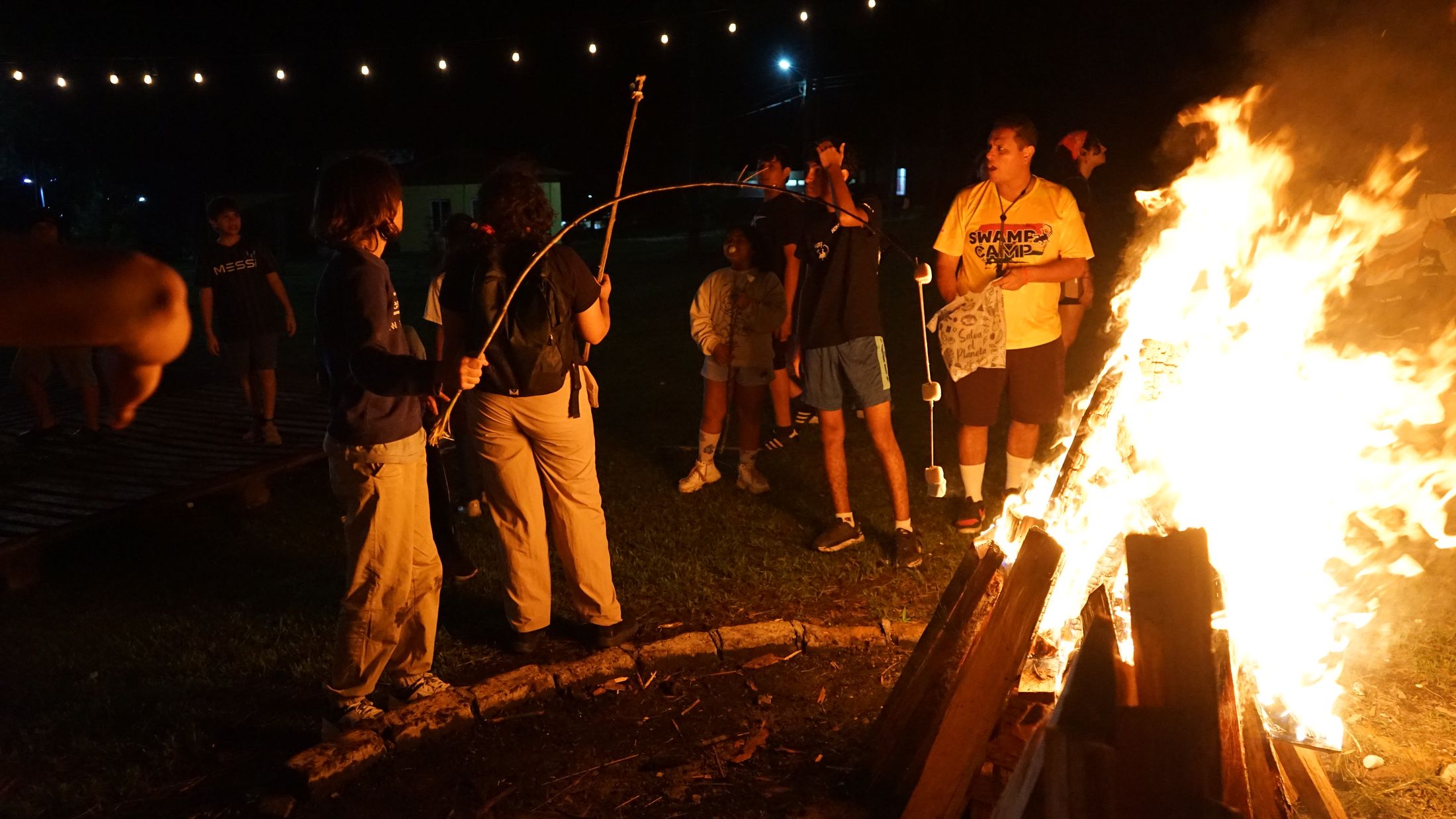 Campers gathered around a bonfire at night
