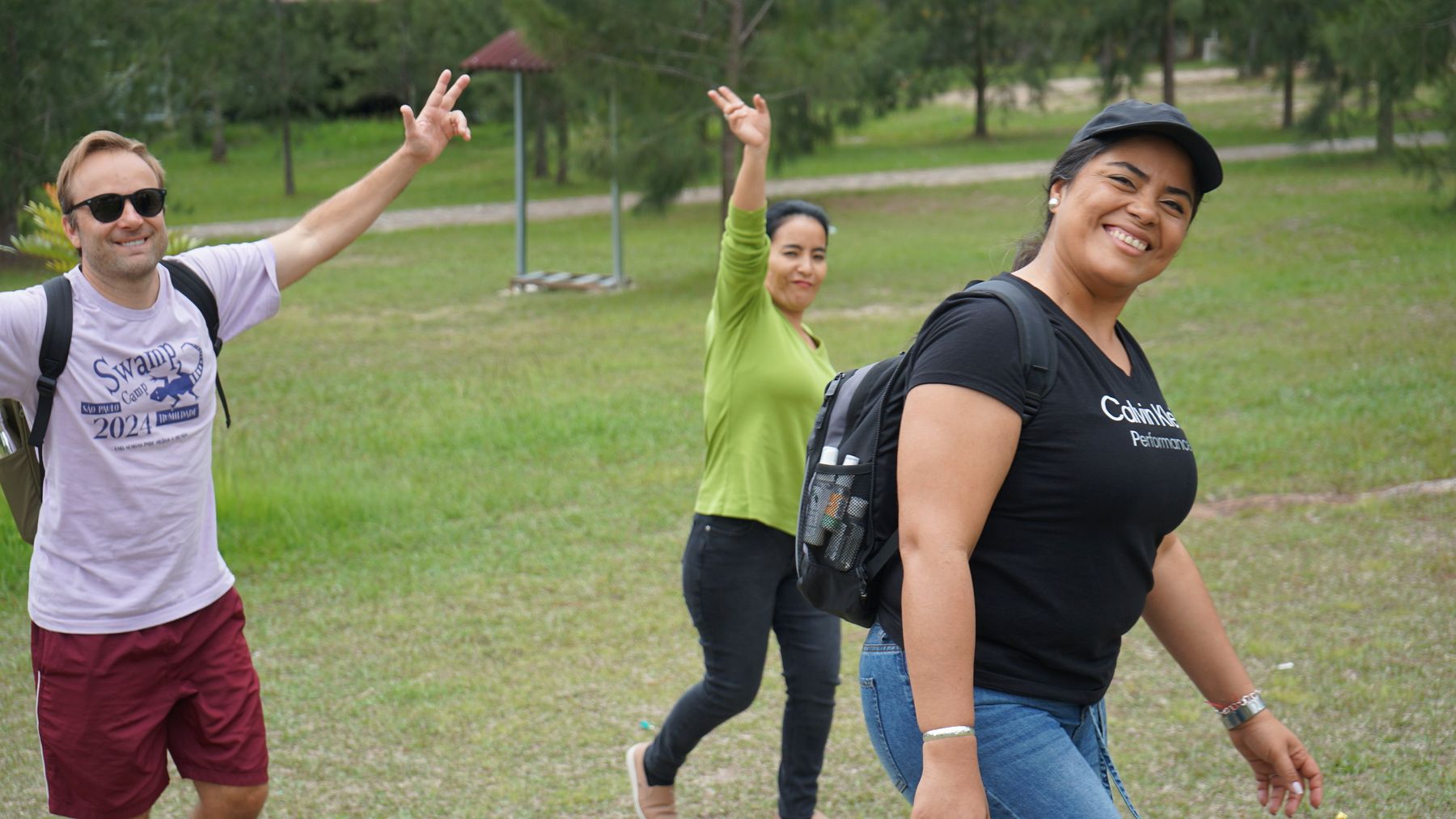 Three Swamp Corps team members waving on the camp lawn