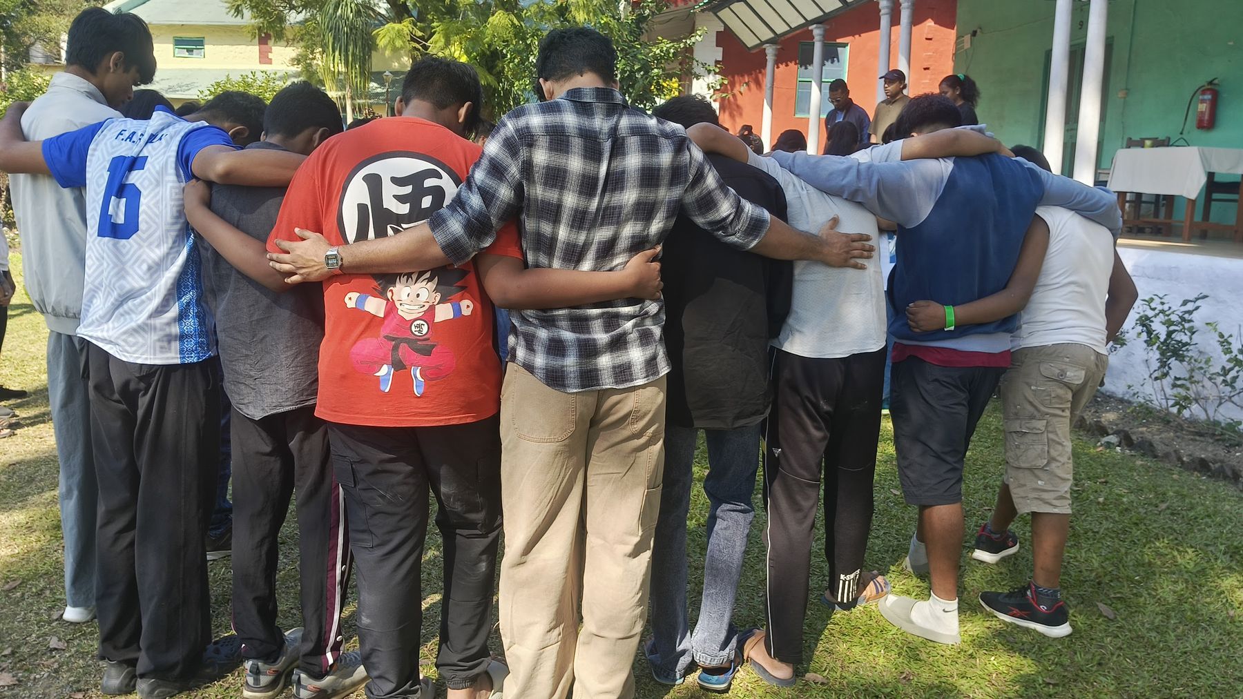 Boys with arms over each other's shoulders in a prayer huddle