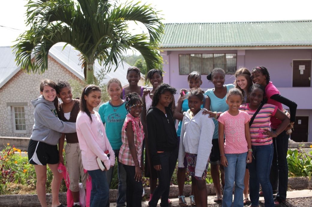 Counselors standing with their team of younger girls in front of the cabins