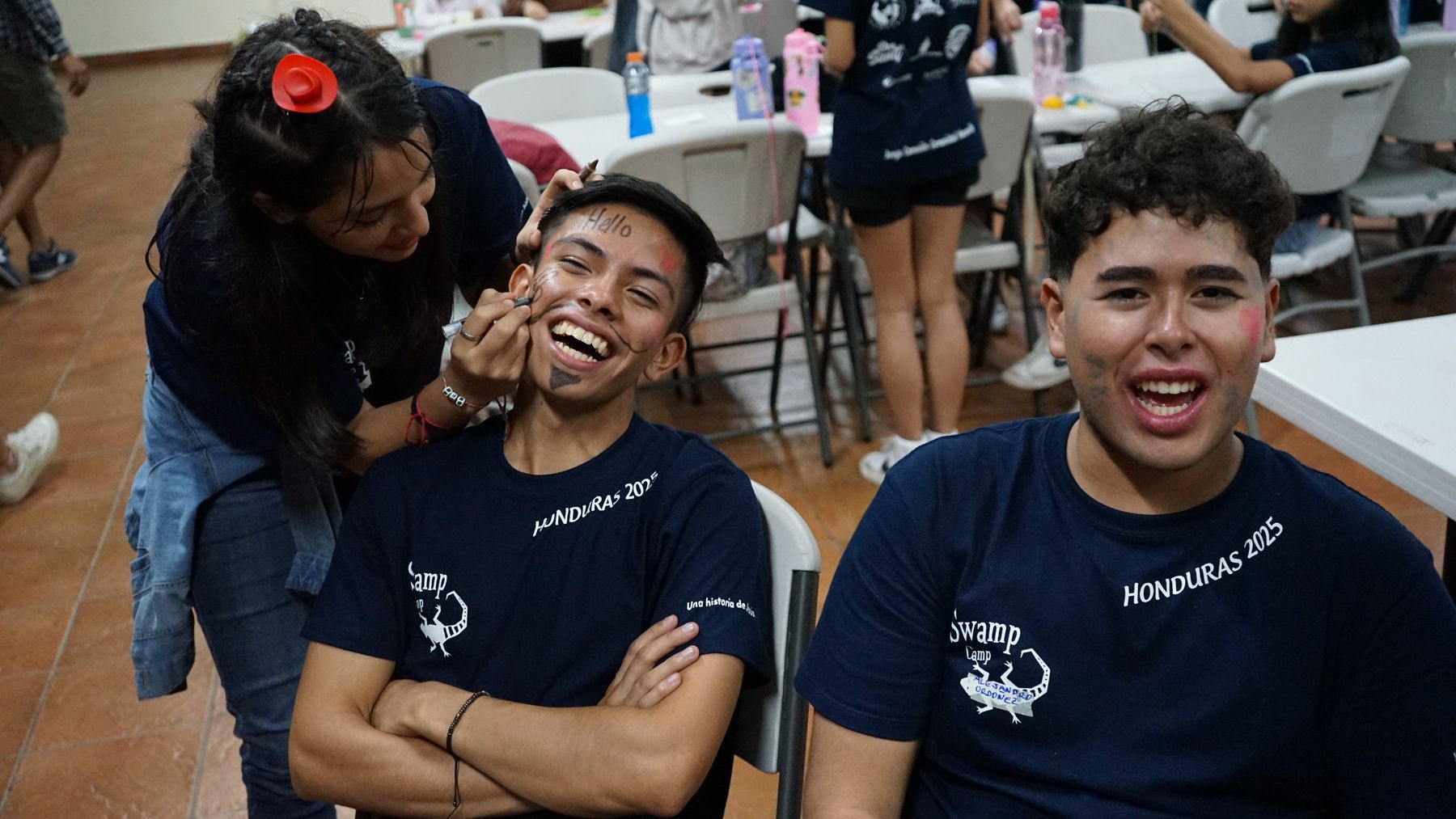 A counselor laughing while his face is painted